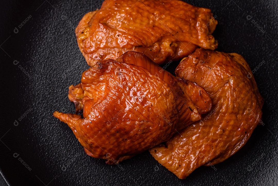 Deliciosas coxas de frango frito ou defumado grelhadas com especiarias e ervas sobre fundo escuro de concreto