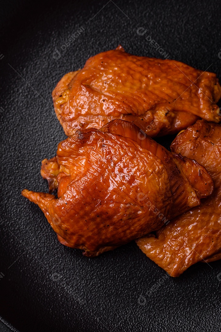 Deliciosas coxas de frango frito ou defumado grelhadas com especiarias e ervas sobre fundo escuro de concreto