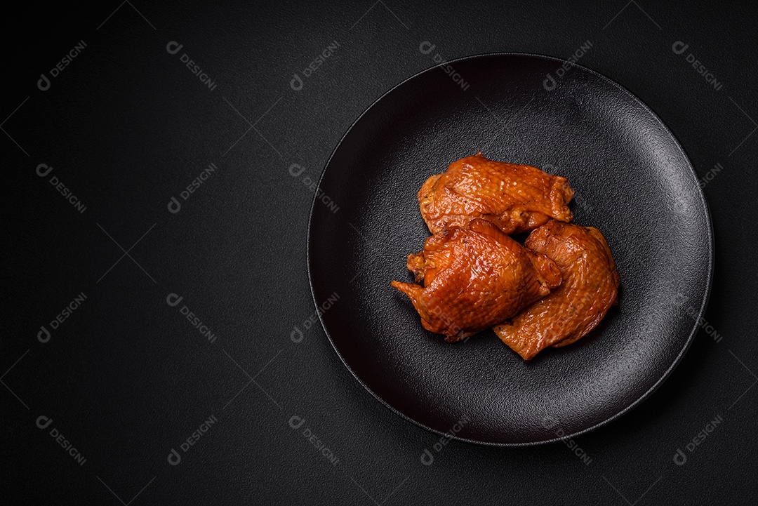 Deliciosas coxas de frango frito ou defumado grelhadas com especiarias e ervas sobre fundo escuro de concreto