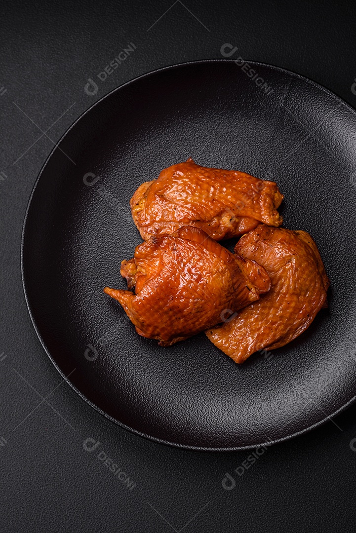 Deliciosas coxas de frango frito ou defumado grelhadas com especiarias e ervas sobre fundo escuro de concreto