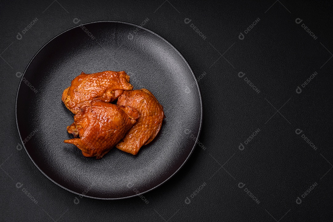 Deliciosas coxas de frango frito ou defumado grelhadas com especiarias e ervas sobre fundo escuro de concreto