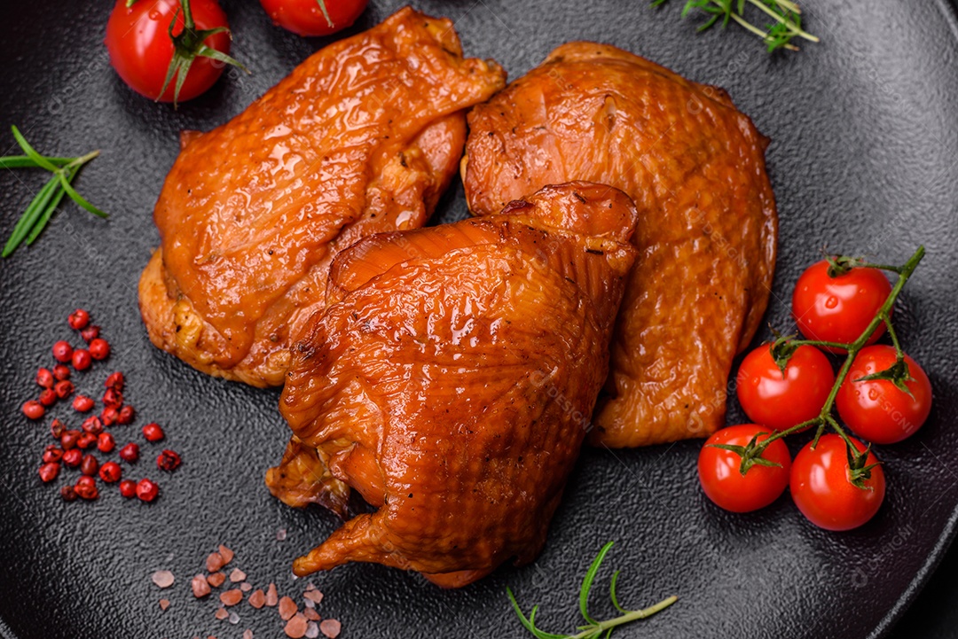 Deliciosas coxas de frango frito ou defumado grelhadas com especiarias e ervas sobre fundo escuro de concreto