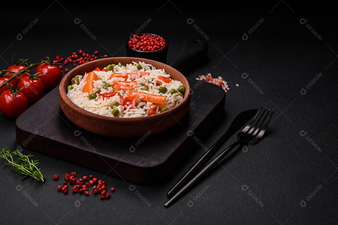 Delicioso arroz cozido com legumes ou risoto com sal, especiarias e ervas num prato cerâmico sobre fundo escuro de concreto