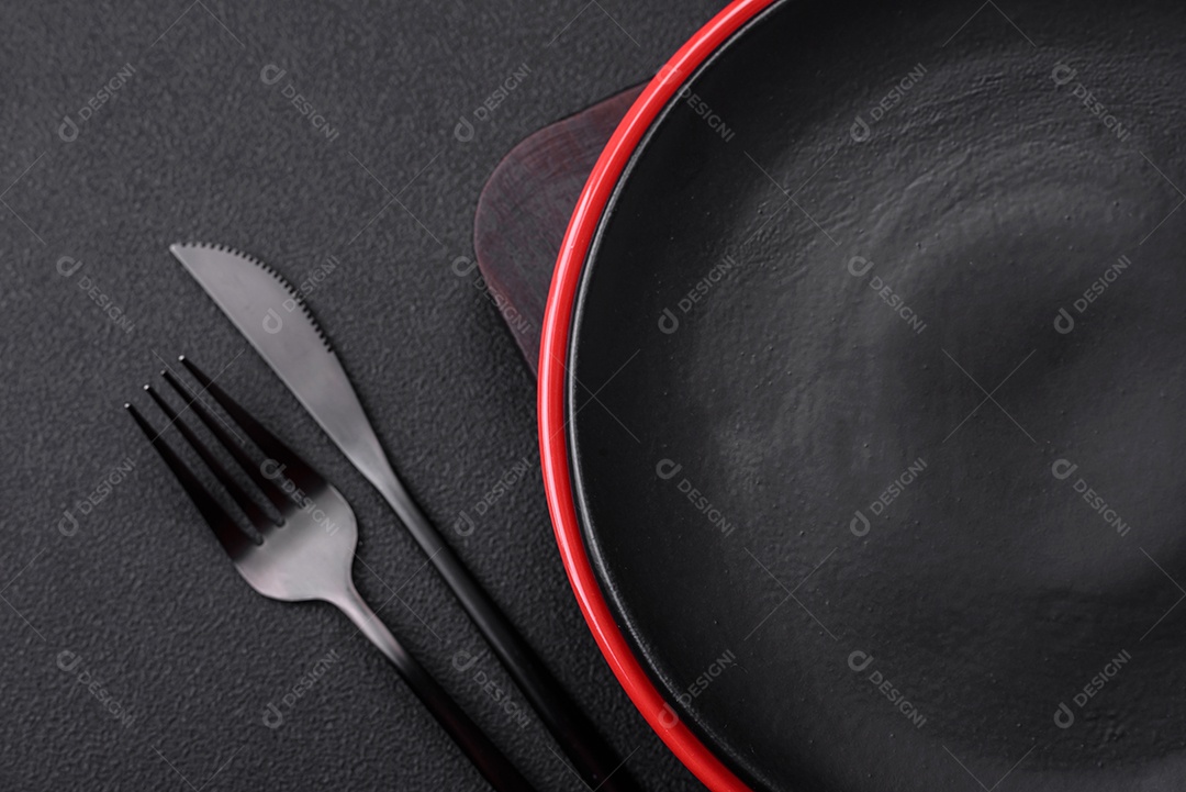 Placa cerâmica vazia em fundo de concreto texturizado escuro. Talheres na mesa da cozinha