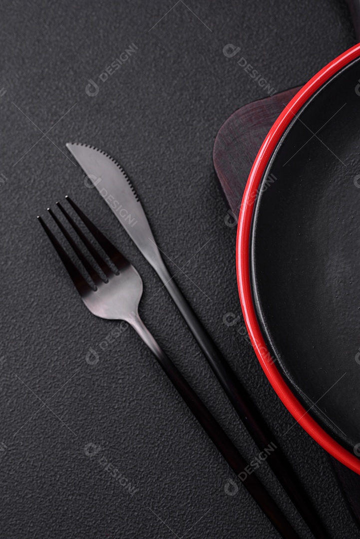 Placa cerâmica vazia em fundo de concreto texturizado escuro. Talheres na mesa da cozinha