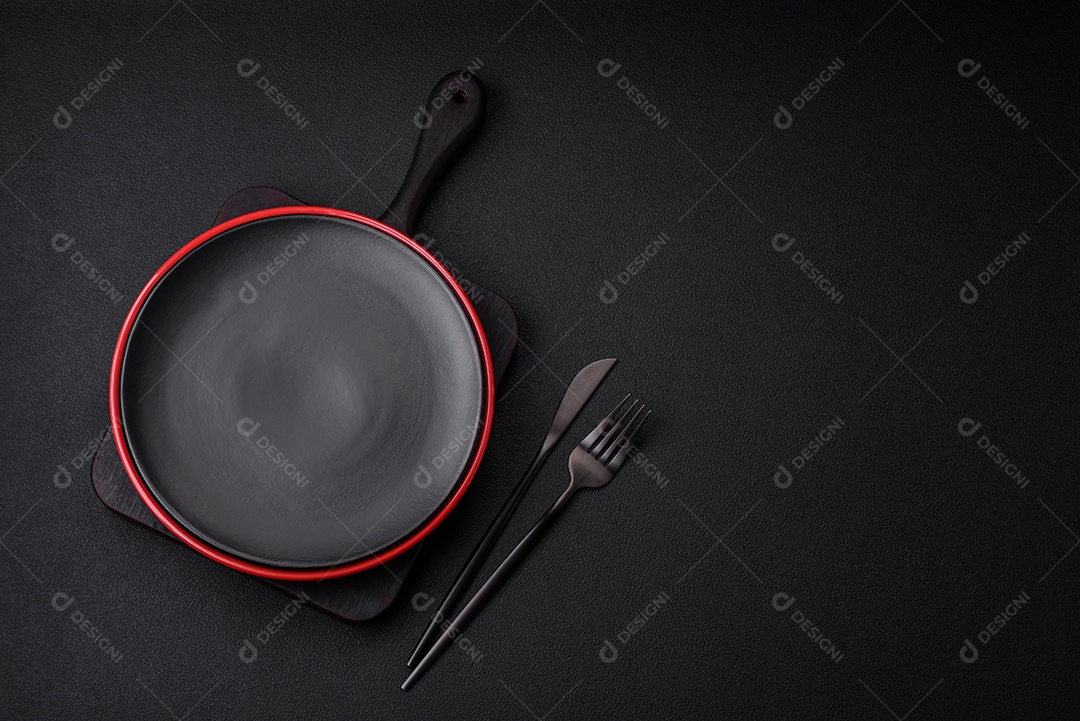 Placa cerâmica vazia em fundo de concreto texturizado escuro. Talheres na mesa da cozinha