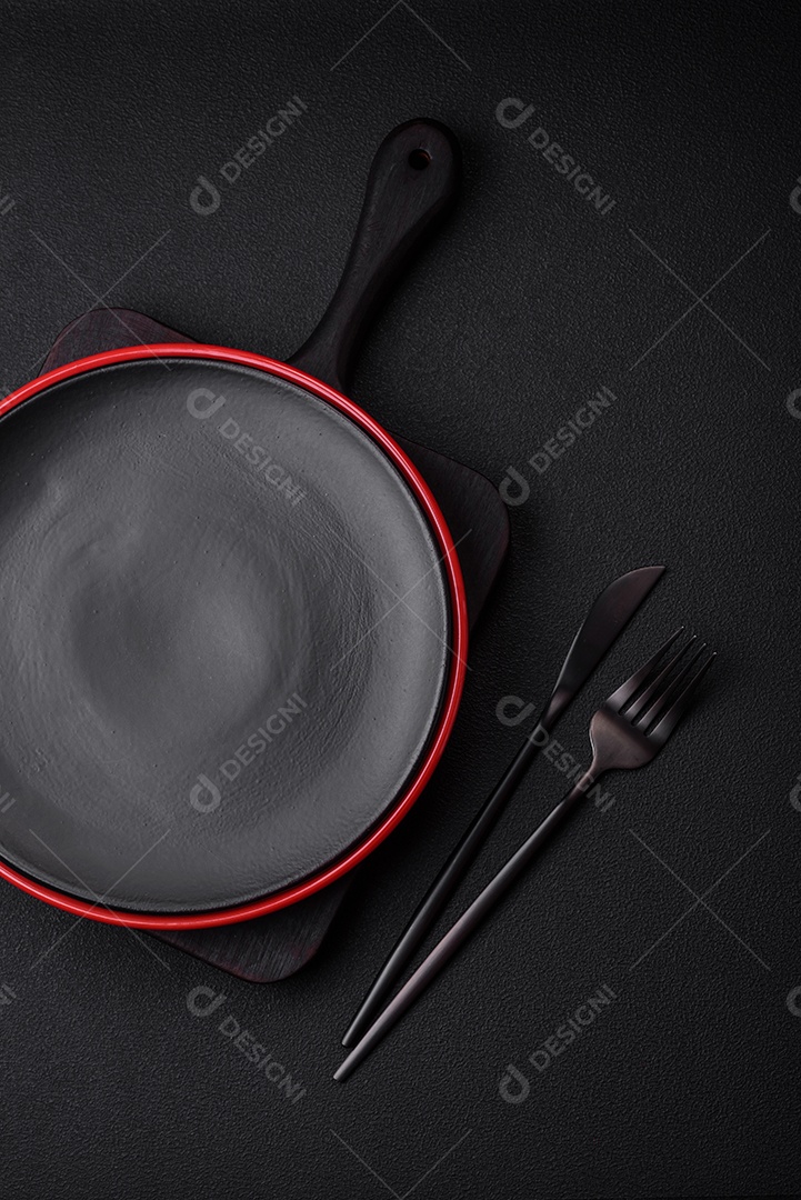 Placa cerâmica vazia em fundo de concreto texturizado escuro. Talheres na mesa da cozinha