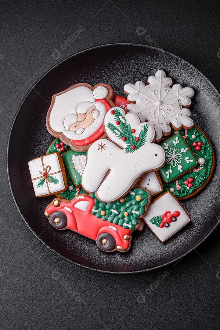 Lindos biscoitos de gengibre caseiros coloridos e brilhantes em uma placa de cerâmica sobre um fundo escuro de concreto