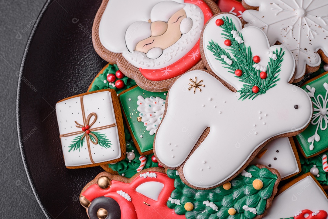 Lindos biscoitos de gengibre caseiros coloridos e brilhantes em uma placa de cerâmica sobre um fundo escuro de concreto