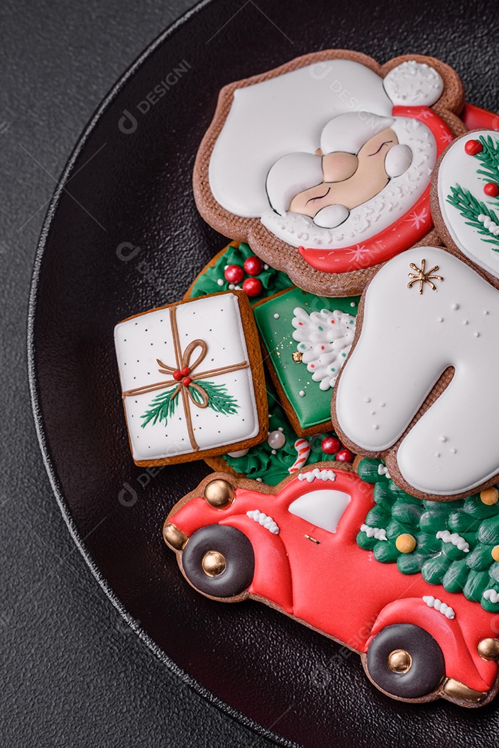 Lindos biscoitos de gengibre caseiros coloridos e brilhantes em uma placa de cerâmica sobre um fundo escuro de concreto