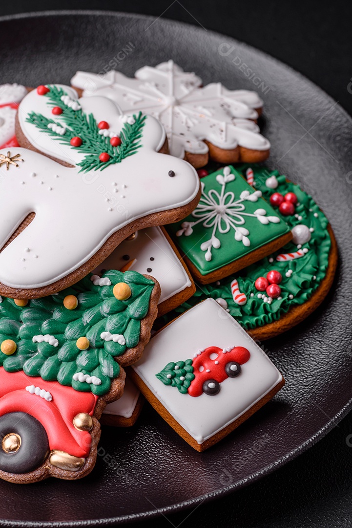 Lindos biscoitos de gengibre caseiros coloridos e brilhantes em uma placa de cerâmica sobre um fundo escuro de concreto