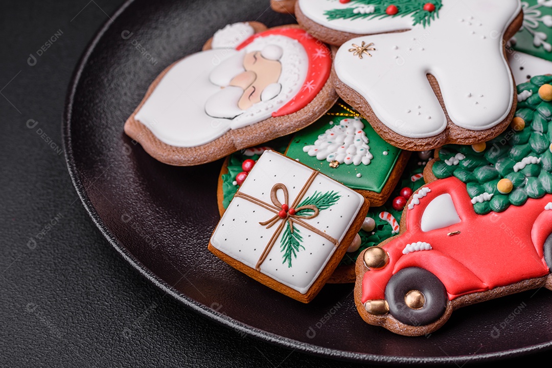 Lindos biscoitos de gengibre caseiros coloridos e brilhantes em uma placa de cerâmica sobre um fundo escuro de concreto