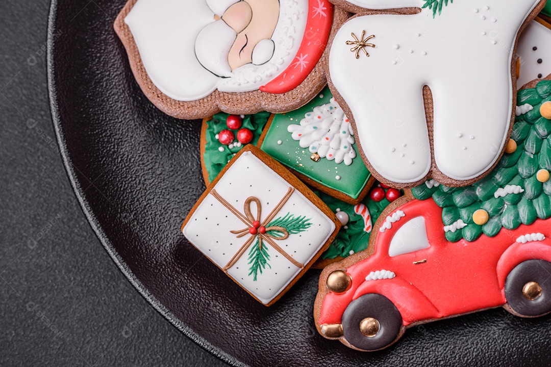 Lindos biscoitos de gengibre caseiros coloridos e brilhantes em uma placa de cerâmica sobre um fundo escuro de concreto