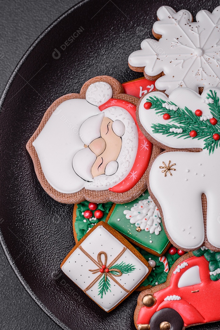 Lindos biscoitos de gengibre caseiros coloridos e brilhantes em uma placa de cerâmica sobre um fundo escuro de concreto