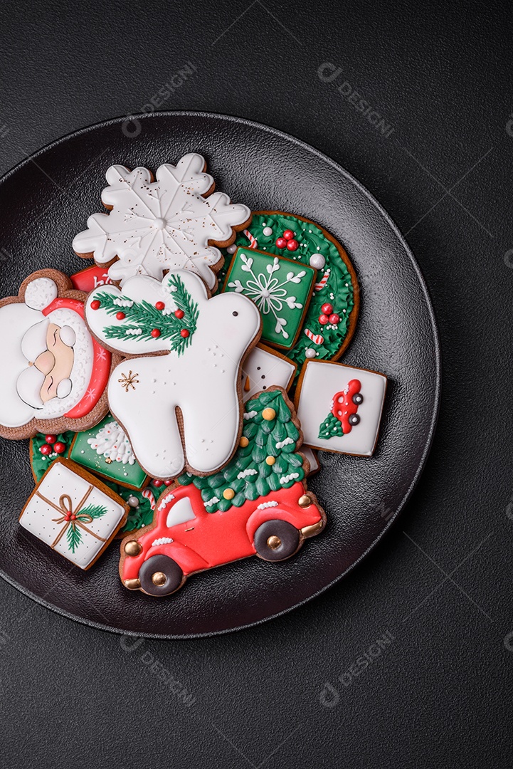 Lindos biscoitos de gengibre caseiros coloridos e brilhantes em uma placa de cerâmica sobre um fundo escuro de concreto