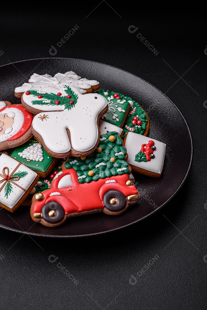 Lindos biscoitos de gengibre caseiros coloridos e brilhantes em uma placa de cerâmica sobre um fundo escuro de concreto