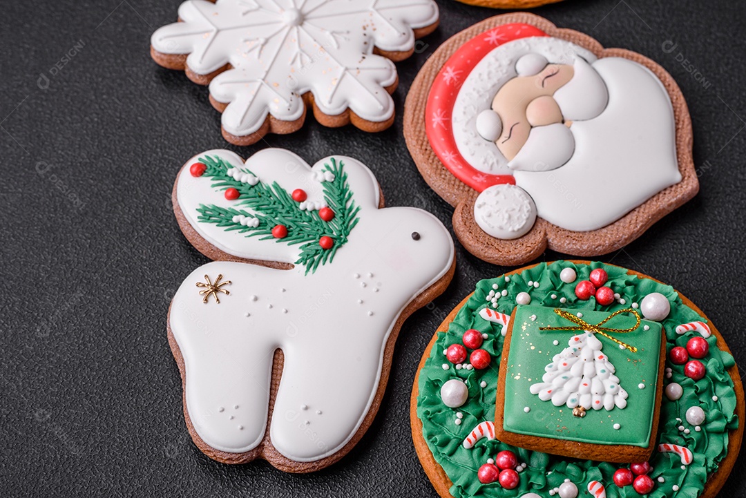 Lindos biscoitos de gengibre caseiros coloridos e brilhantes em uma placa de cerâmica sobre um fundo escuro de concreto