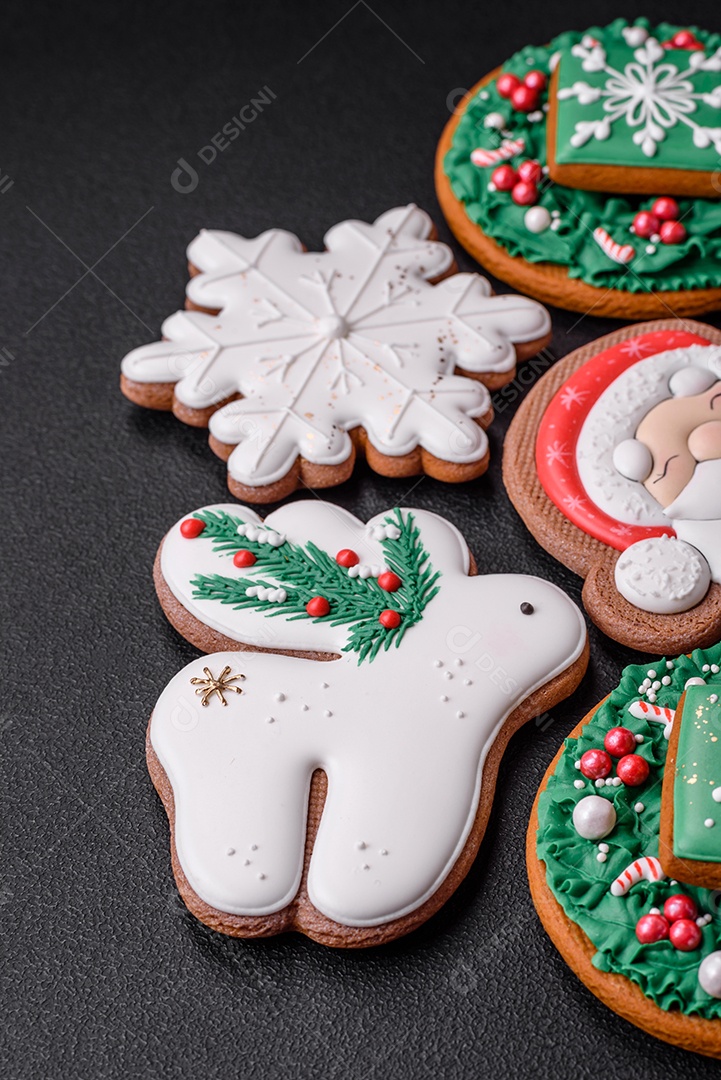 Lindos biscoitos de gengibre caseiros coloridos e brilhantes em uma placa de cerâmica sobre um fundo escuro de concreto
