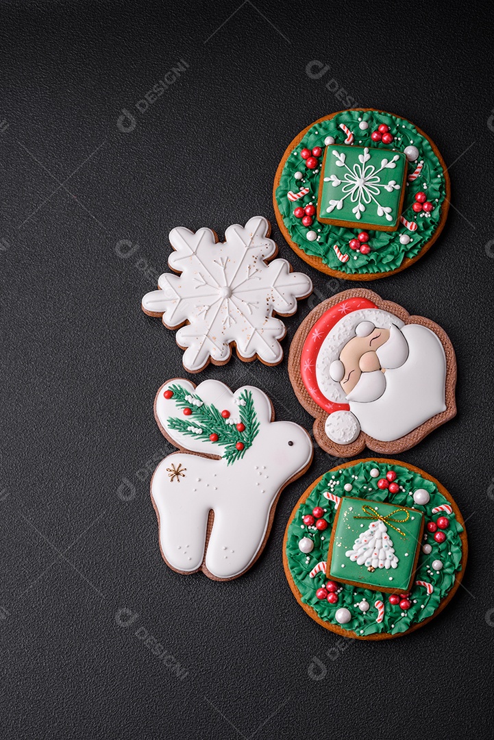 Lindos biscoitos de gengibre caseiros coloridos e brilhantes em uma placa de cerâmica sobre um fundo escuro de concreto