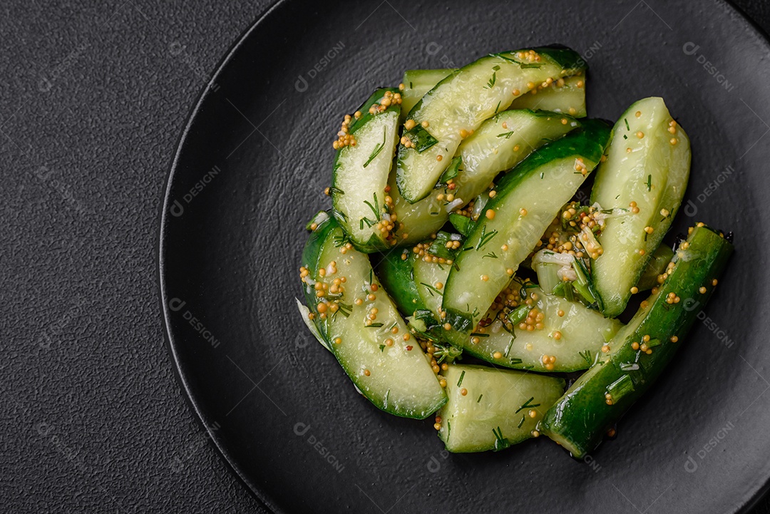Delicioso pepino suculento cortado em grandes fatias com sal, especiarias e mostarda francesa sobre um fundo escuro de concreto