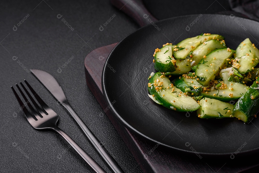 Delicioso pepino suculento cortado em grandes fatias com sal, especiarias e mostarda francesa sobre um fundo escuro de concreto