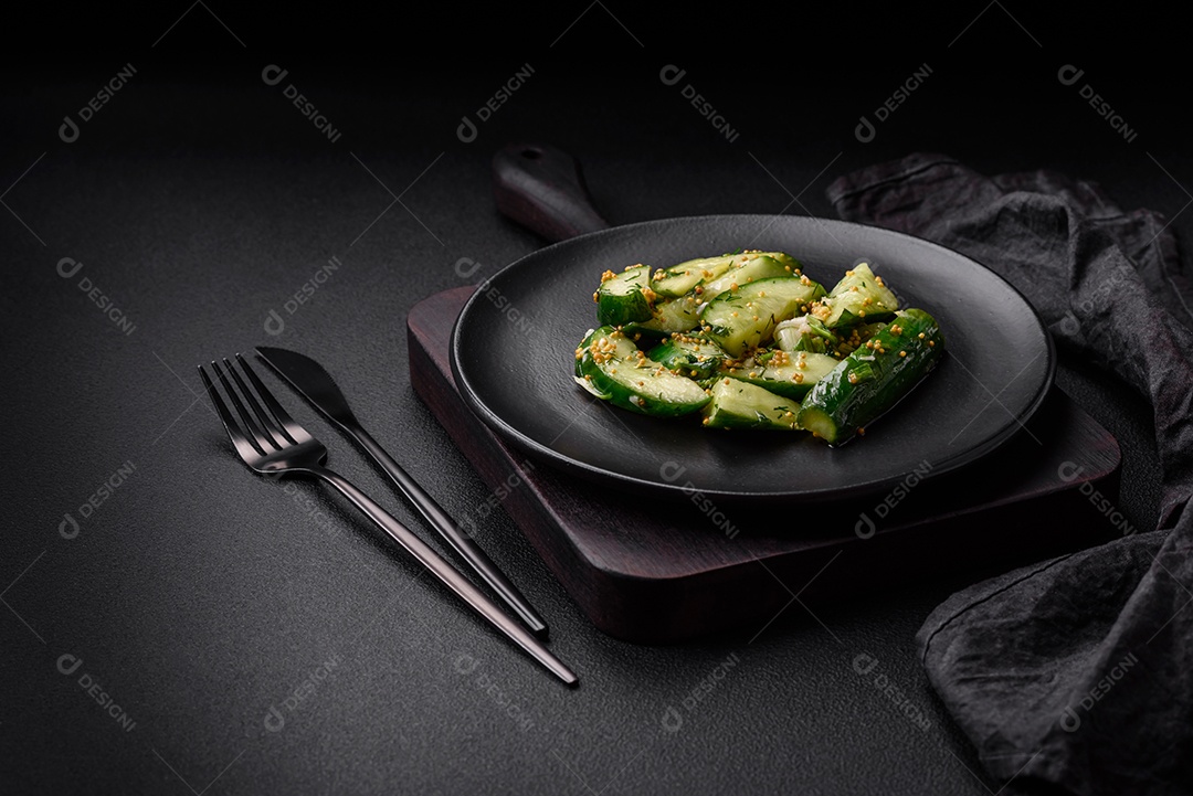 Delicioso pepino suculento cortado em grandes fatias com sal, especiarias e mostarda francesa sobre um fundo escuro de concreto