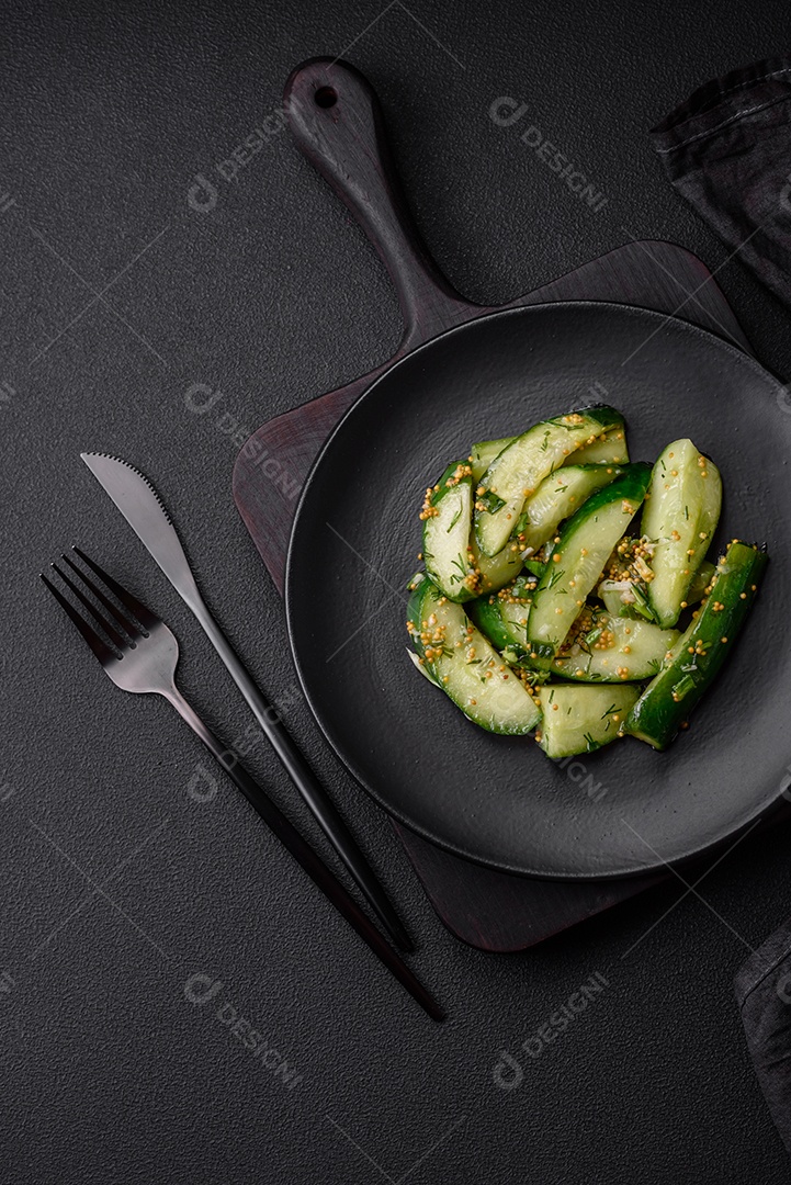 Delicioso pepino suculento cortado em grandes fatias com sal, especiarias e mostarda francesa sobre um fundo escuro de concreto