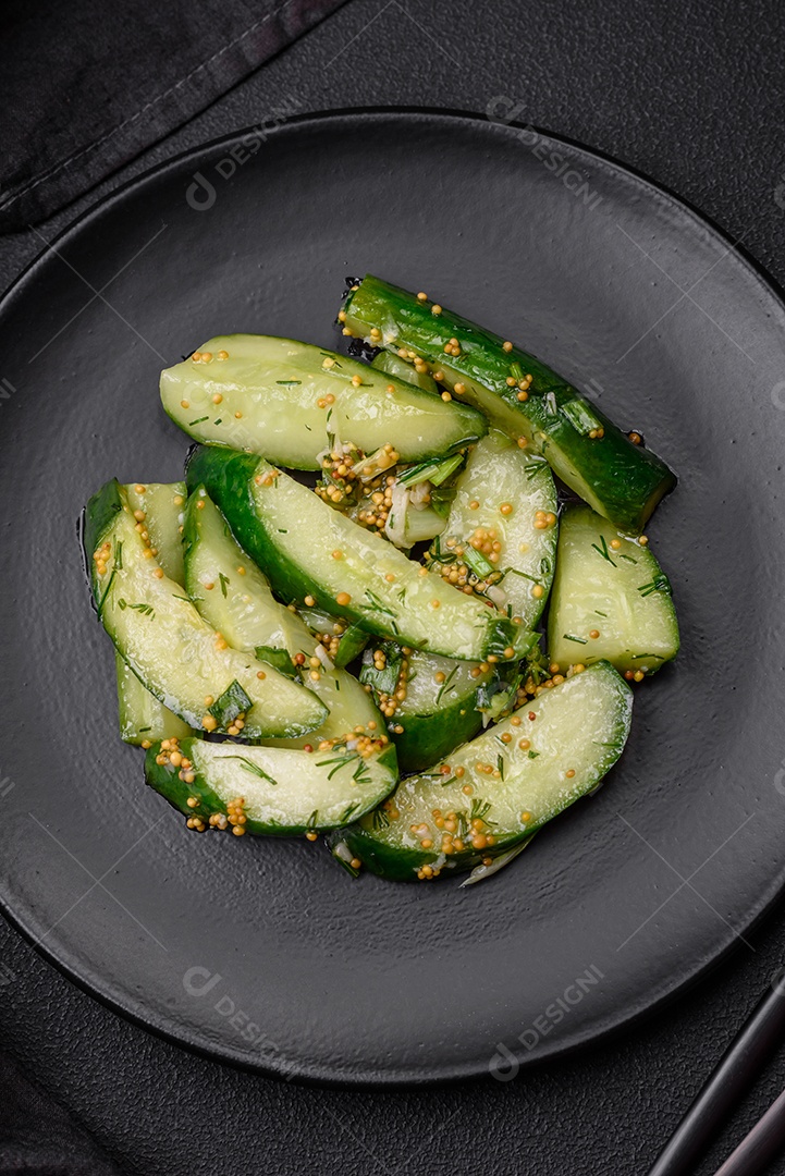 Delicioso pepino suculento cortado em grandes fatias com sal, especiarias e mostarda francesa sobre um fundo escuro de concreto