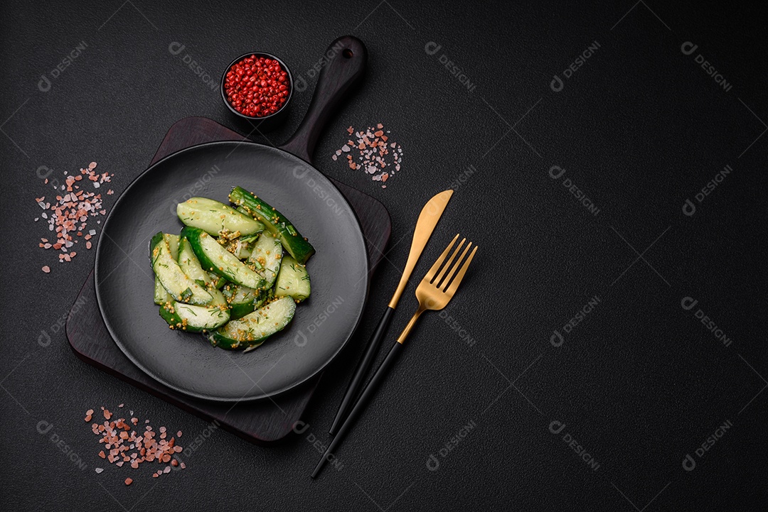 Delicioso pepino suculento cortado em grandes fatias com sal, especiarias e mostarda francesa sobre um fundo escuro de concreto