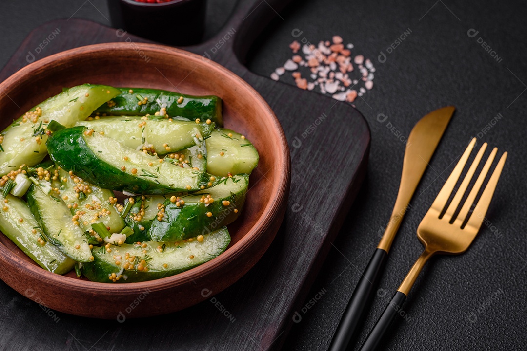 Delicioso pepino suculento cortado em grandes fatias com sal, especiarias e mostarda francesa sobre um fundo escuro de concreto