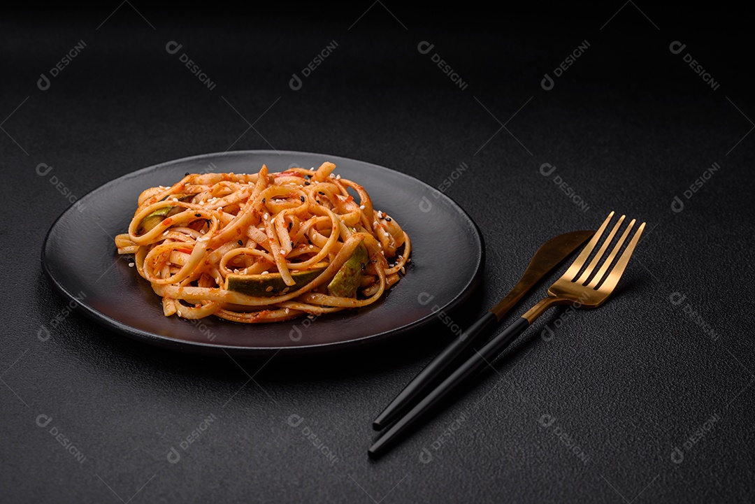 Delicioso prato de udon asiático com legumes, cogumelos, sal e especiarias numa placa cerâmica sobre um fundo escuro de concreto