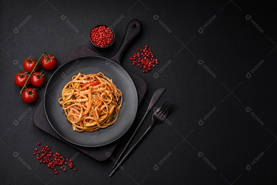 Delicioso prato de udon asiático com legumes, cogumelos, sal e especiarias numa placa cerâmica sobre um fundo escuro de concreto