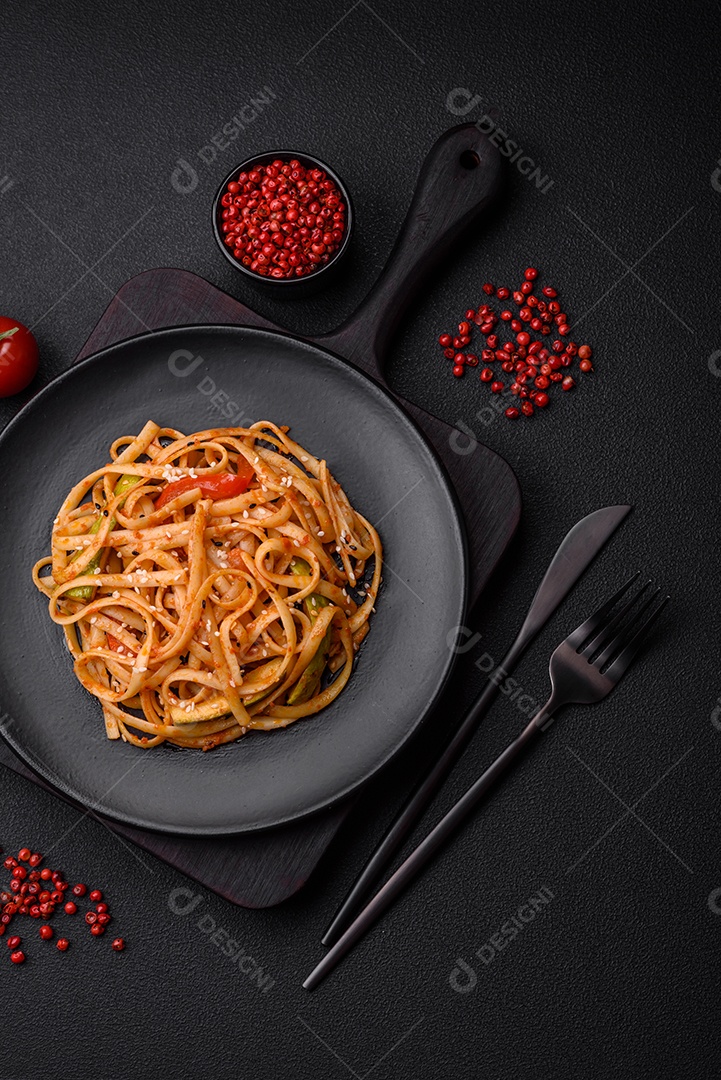 Delicioso prato de udon asiático com legumes, cogumelos, sal e especiarias numa placa cerâmica sobre um fundo escuro de concreto