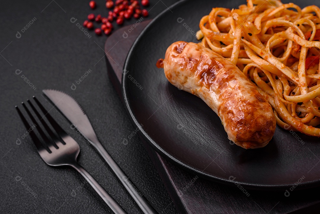 Deliciosas salsichas grelhadas suculentas com sal, especiarias e ervas numa placa cerâmica sobre um fundo escuro de concreto