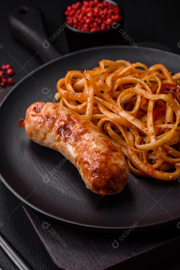 Deliciosas salsichas grelhadas suculentas com sal, especiarias e ervas numa placa cerâmica sobre um fundo escuro de concreto