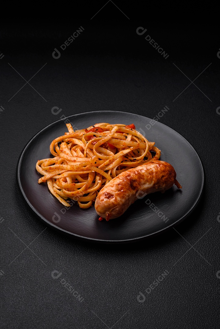 Deliciosas salsichas grelhadas suculentas com sal, especiarias e ervas numa placa cerâmica sobre um fundo escuro de concreto