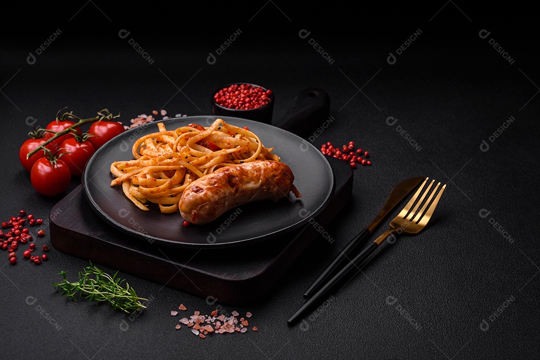 Deliciosas salsichas grelhadas suculentas com sal, especiarias e ervas numa placa cerâmica sobre um fundo escuro de concreto