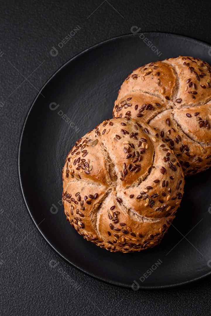 Delicioso pão crocante fresco assado com sementes e grãos sobre um fundo escuro de concreto