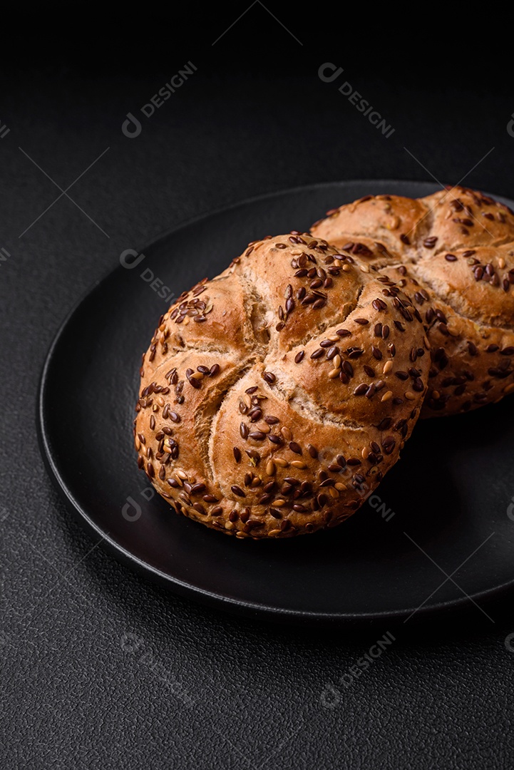Delicioso pão crocante fresco assado com sementes e grãos sobre um fundo escuro de concreto