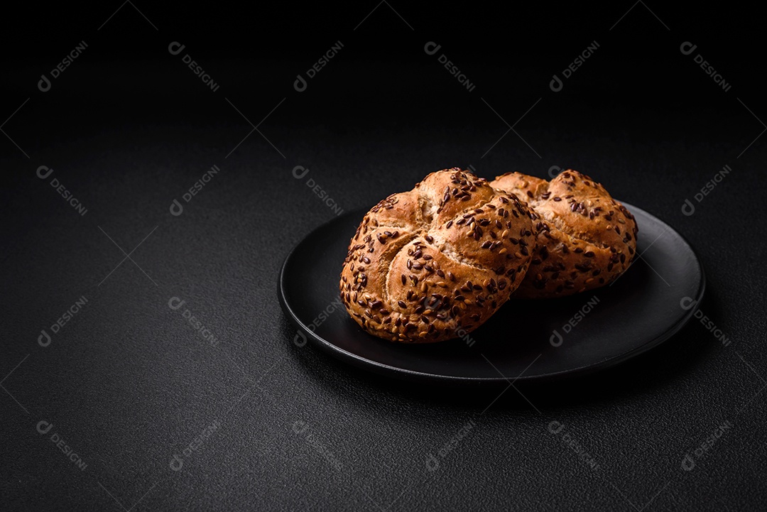 Delicioso pão crocante fresco assado com sementes e grãos sobre um fundo escuro de concreto