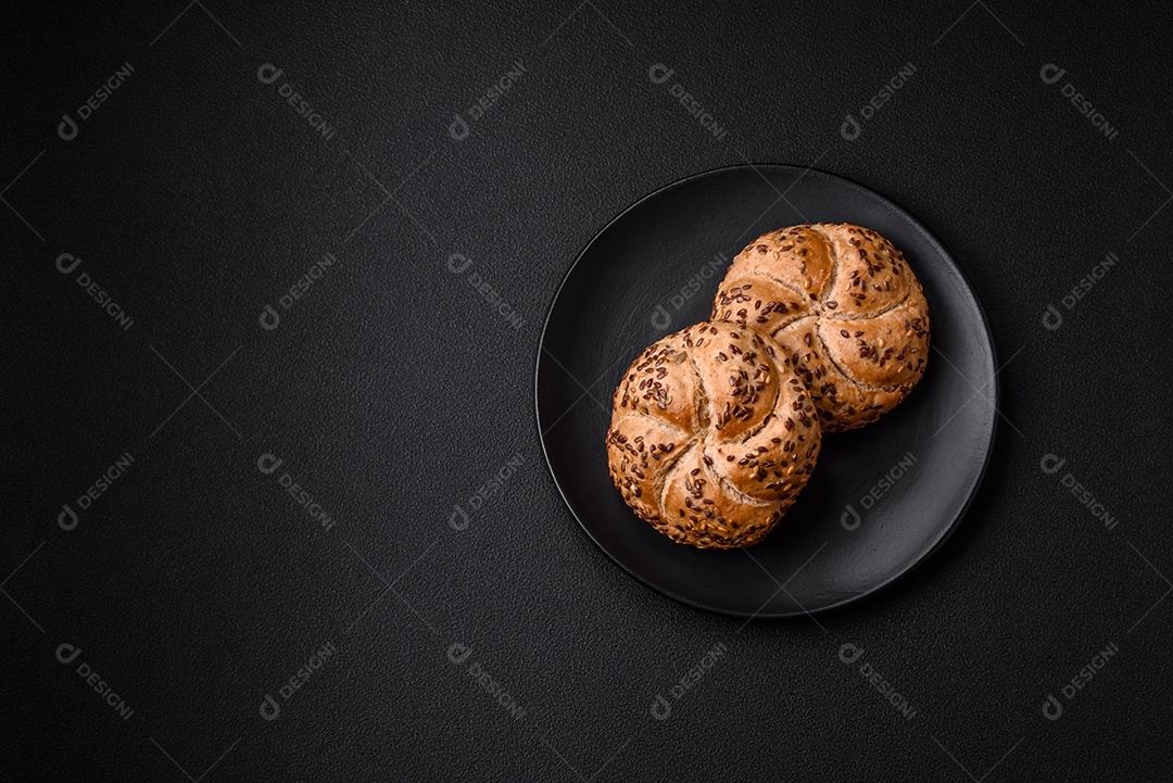 Delicioso pão crocante fresco assado com sementes e grãos sobre um fundo escuro de concreto