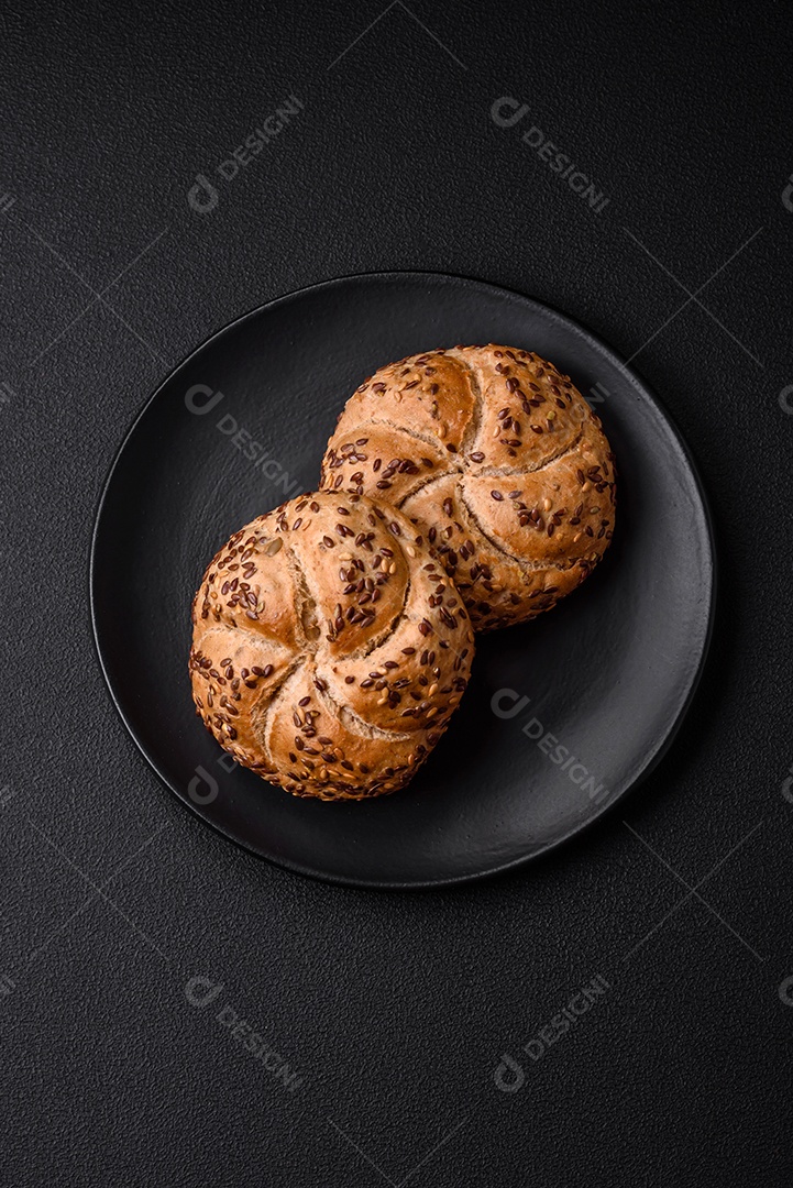 Delicioso pão crocante fresco assado com sementes e grãos sobre um fundo escuro de concreto