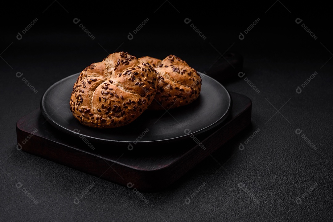 Delicioso pão crocante fresco assado com sementes e grãos sobre um fundo escuro de concreto