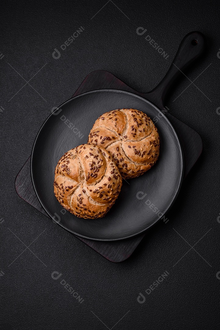 Delicioso pão crocante fresco assado com sementes e grãos sobre um fundo escuro de concreto