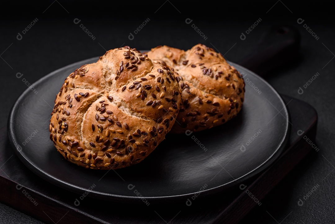 Delicioso pão crocante fresco assado com sementes e grãos sobre um fundo escuro de concreto