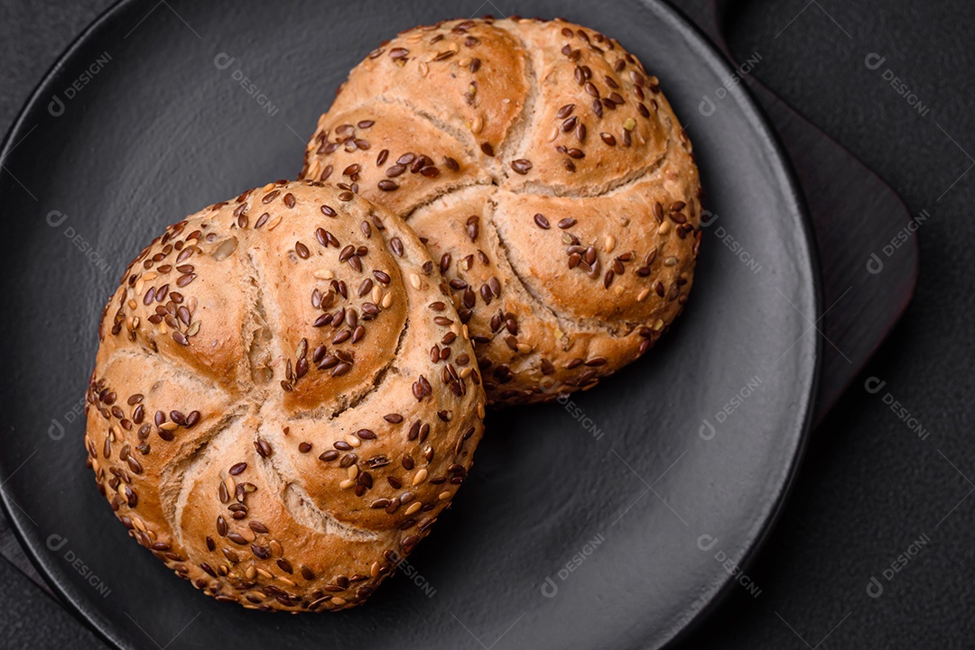 Delicioso pão crocante fresco assado com sementes e grãos sobre um fundo escuro de concreto