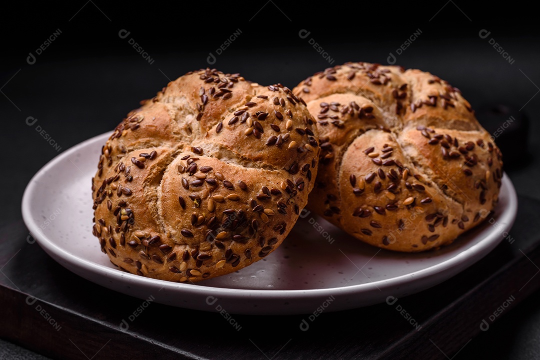 Delicioso pão crocante fresco assado com sementes e grãos sobre um fundo escuro de concreto