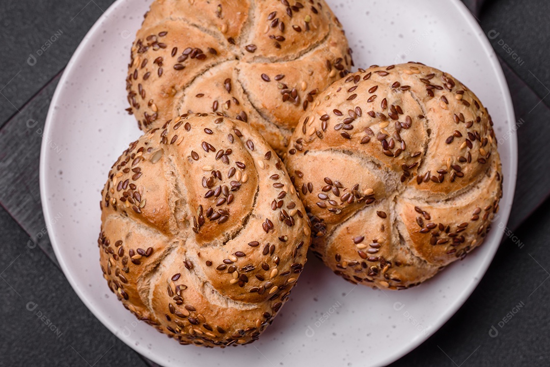 Delicioso pão crocante fresco assado com sementes e grãos sobre um fundo escuro de concreto