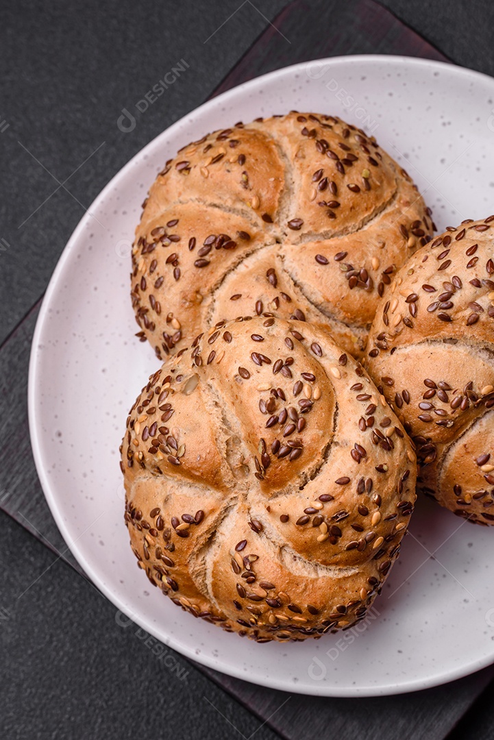 Delicioso pão crocante fresco assado com sementes e grãos sobre um fundo escuro de concreto