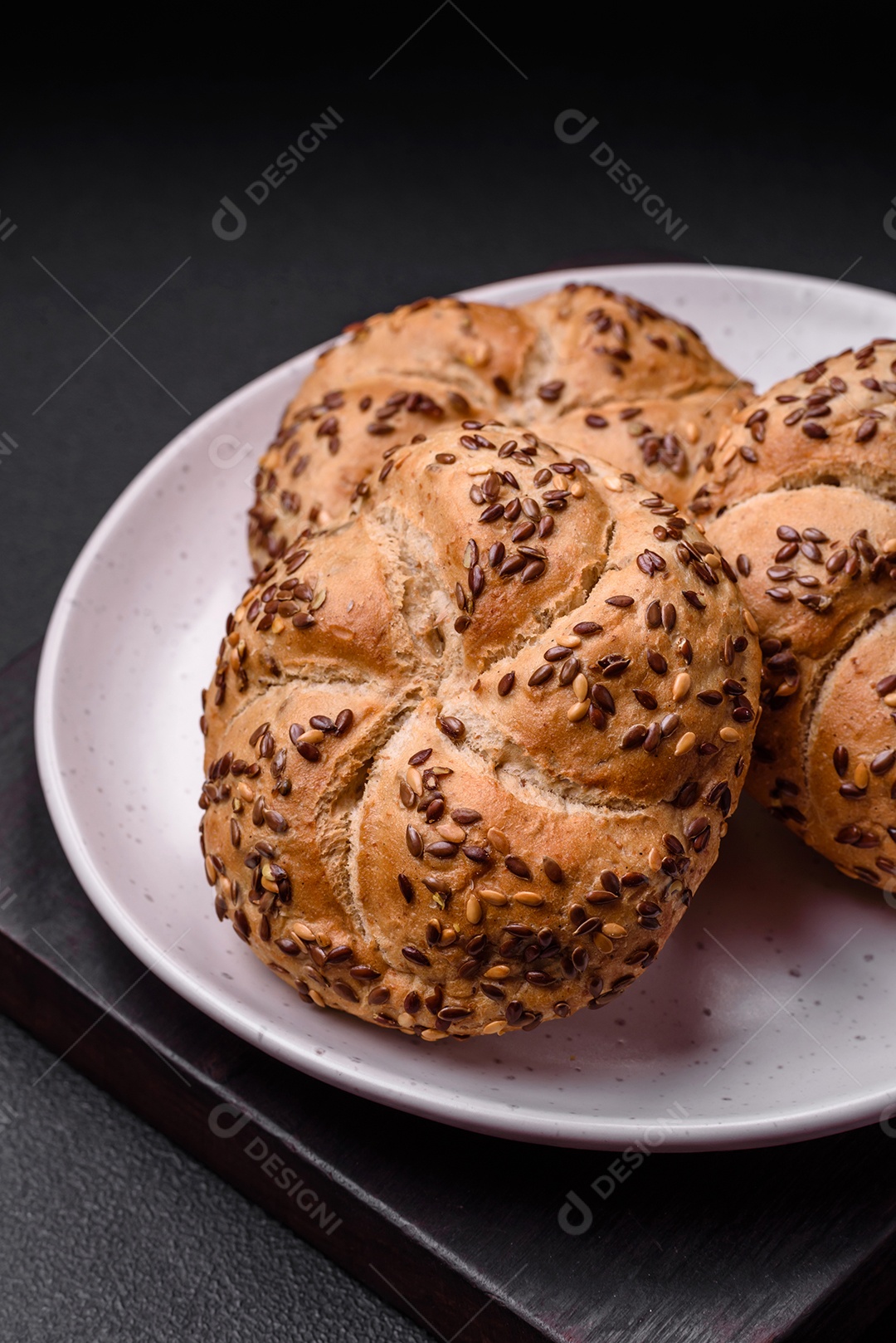 Delicioso pão crocante fresco assado com sementes e grãos sobre um fundo escuro de concreto